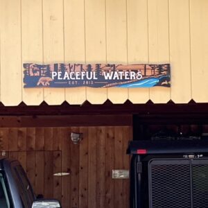 Multicolored Cabin Sign with River Imagery